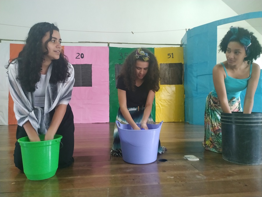 tres discentes encenando a lavagem de um chao na peça