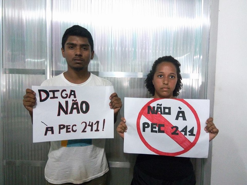 Dois alunos segurando cartazes com dizeres contrários à PEC 241
