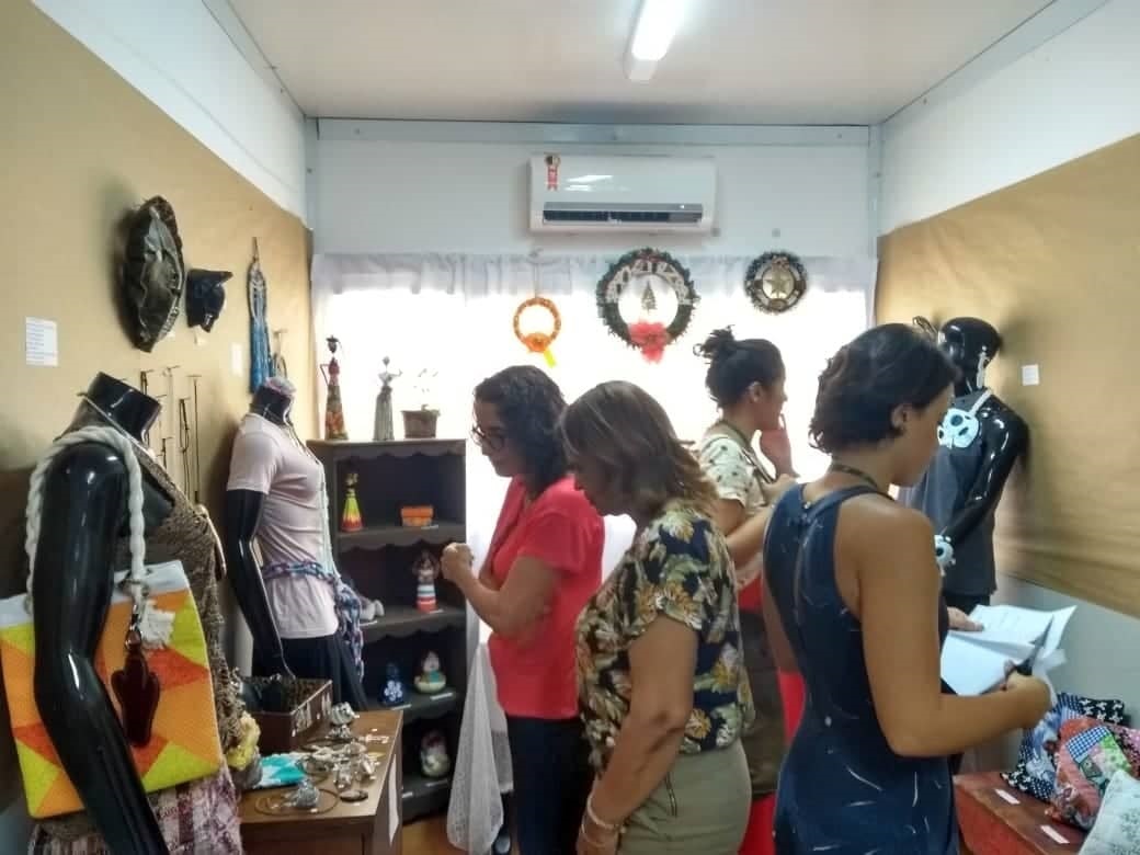 pessoas visitando a sala com exposição de peças artesanais